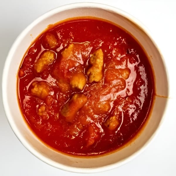 A white bowl filled with By The Bucket's Italian gnocchi in a rich red tomato sauce.