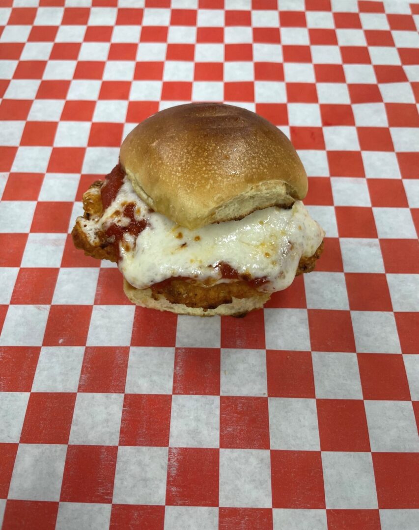 A meatball sandwich sitting on top of a checkered table cloth.